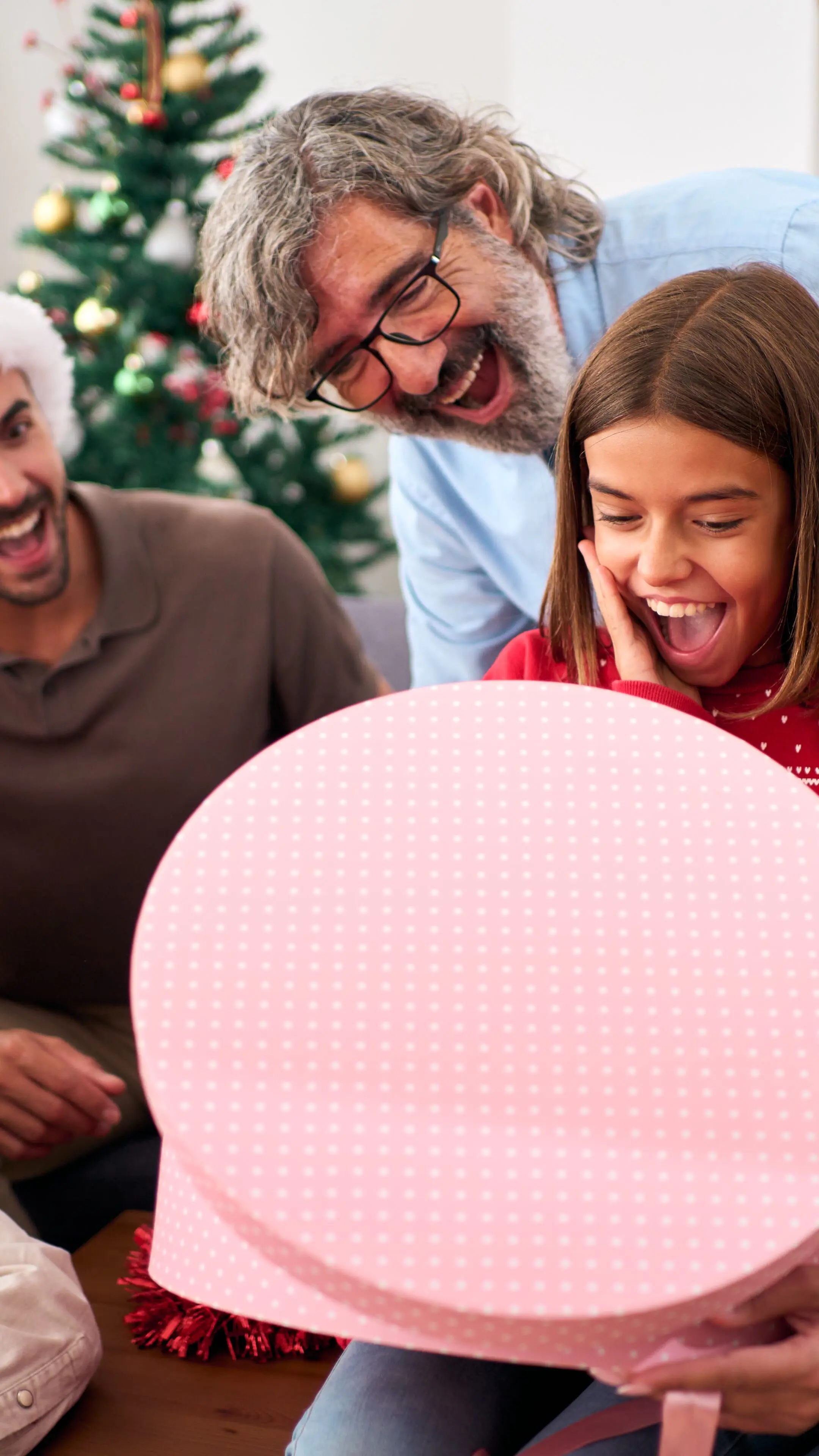 Eine glückliche und aufgeregte Familie ist zu Hause versammelt, während überraschte Menschen Weihnachtsgeschenke öffnen.